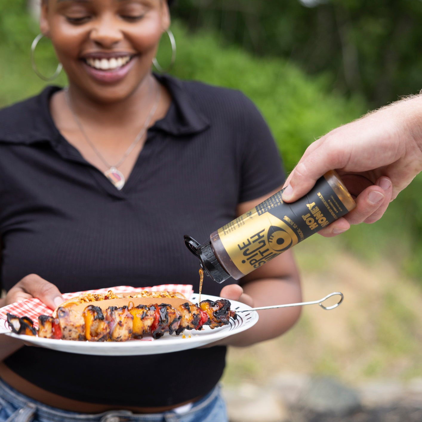 Spicy honey squeeze bottle next to grilled skewers