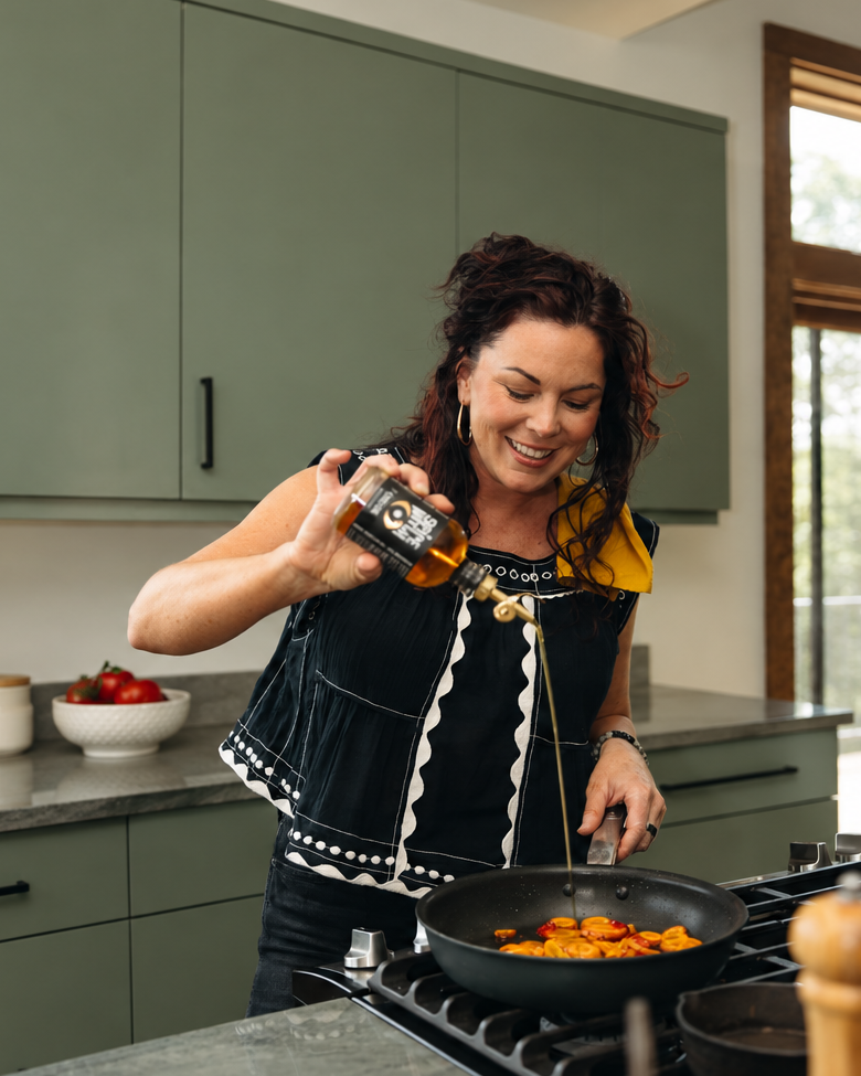 Sabrina Hill, founder of Spice Witch, pouring Spice Witch Chili Oil into a skillet in her kitchen