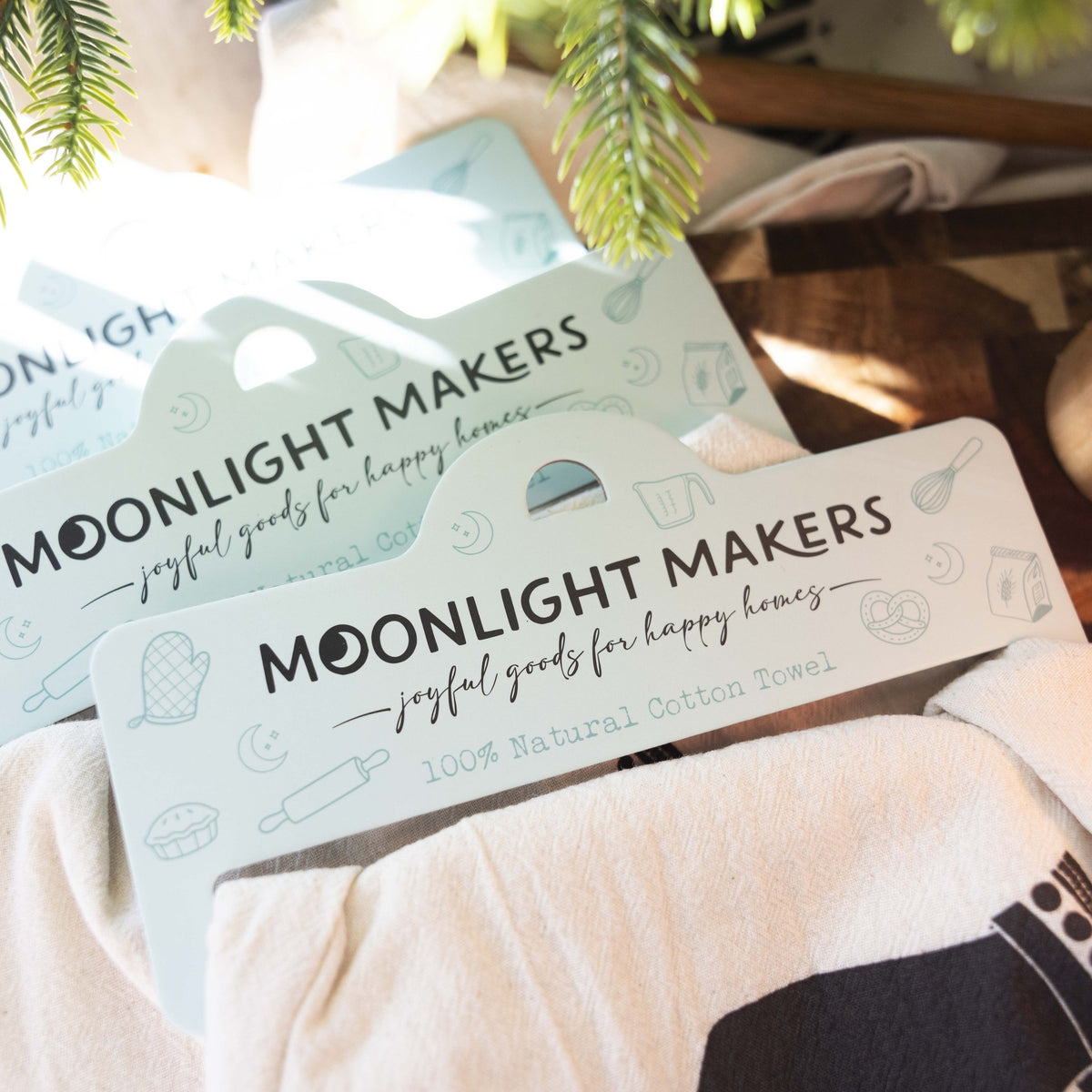 Moonlight Makers hang tags reading 100% Natural Cotton Towel on the Kitchen Magician tea towel