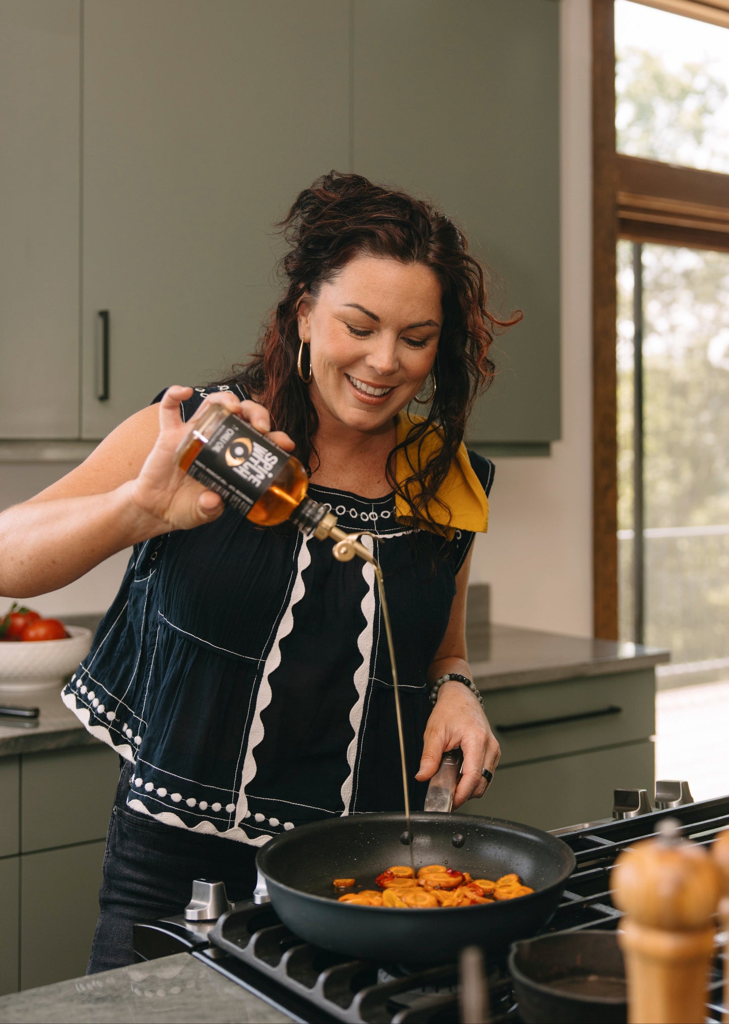 Woman cooking in a kitchen, holding a bottle of whiskey.