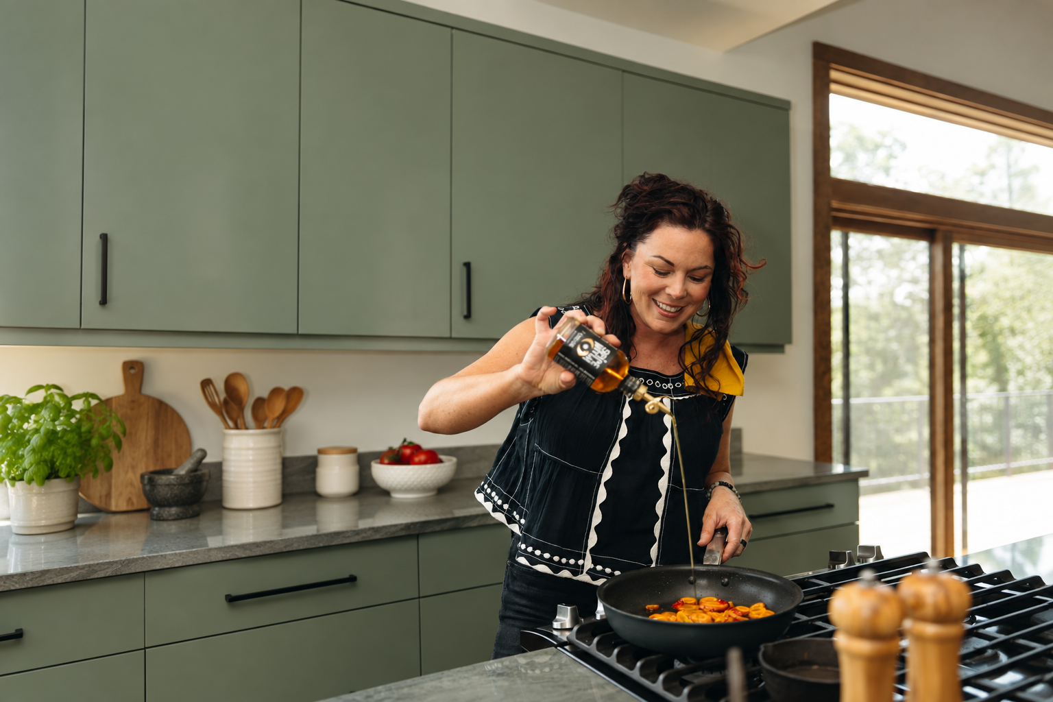 Sabrina Hill, founder of Spice Witch, pouring Spice Witch Chili Oil into a skillet in her kitchen