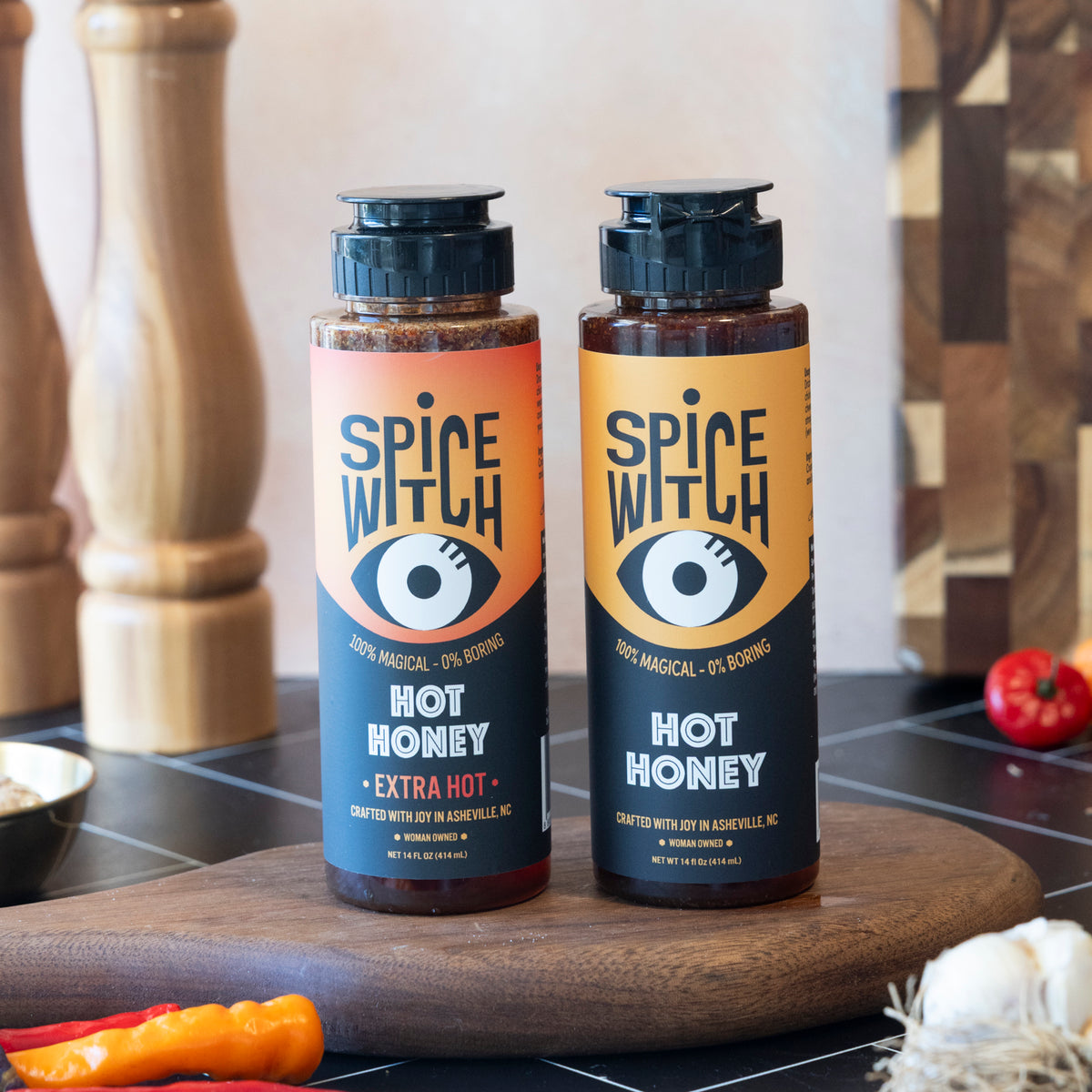 Spice Witch Hot Honey Duo — one Hot Honey and one Extra Hot Honey 14 fl oz squeeze bottle on a wood board